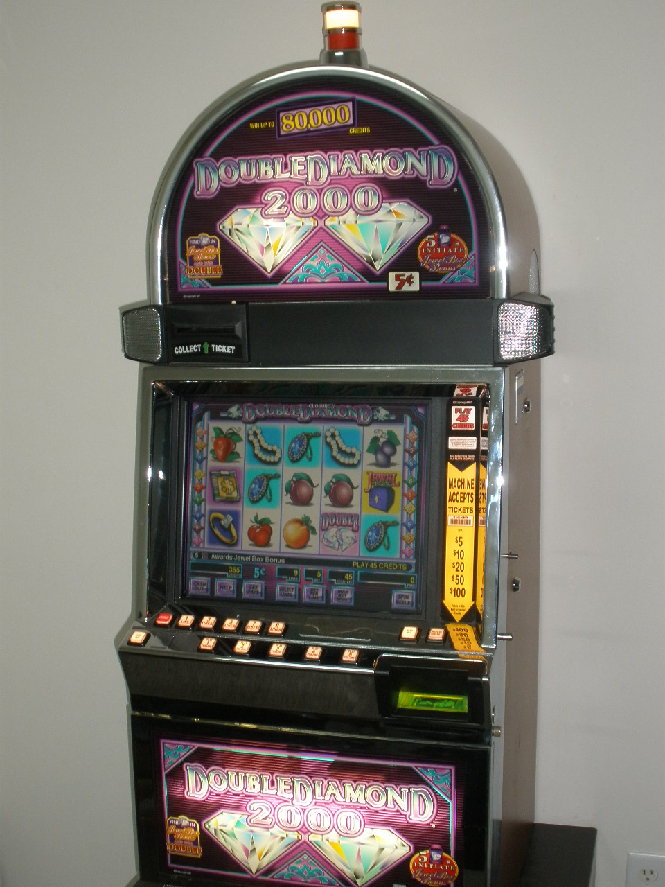 An IGT Double Diamond 2000 slot machine cabinet — illuminated reels of fruit and jewel symbols above a row of physical buttons.